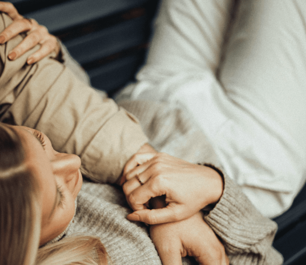 Paar liegt eng umschlungen und hält sich an den Händen – Symbol für Nähe, Vertrauen und emotionale Verbindung.