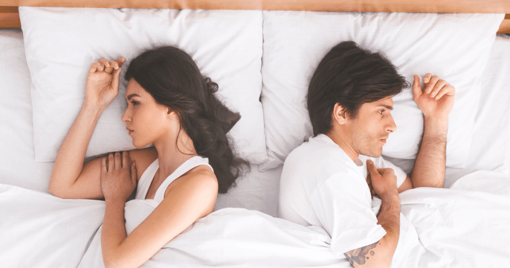 Paar liegt im Bett voneinander abgewandt · emotionale Distanz in der Beziehung