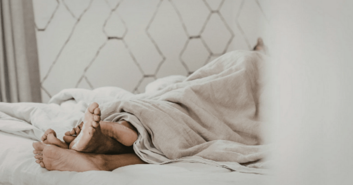 Zwei Menschen liegen eng aneinander im Bett · Füße sichtbar · warme, ruhige Stimmung