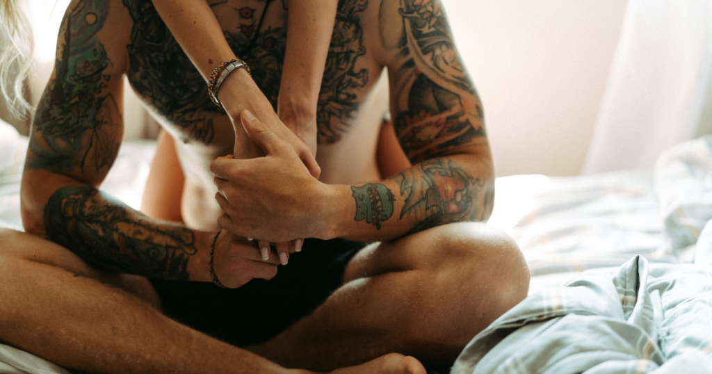 Sex initiieren ohne Druck: Tattooierte Arme umarmen sich nah · Berührung als sichere Einladung zu Intimität