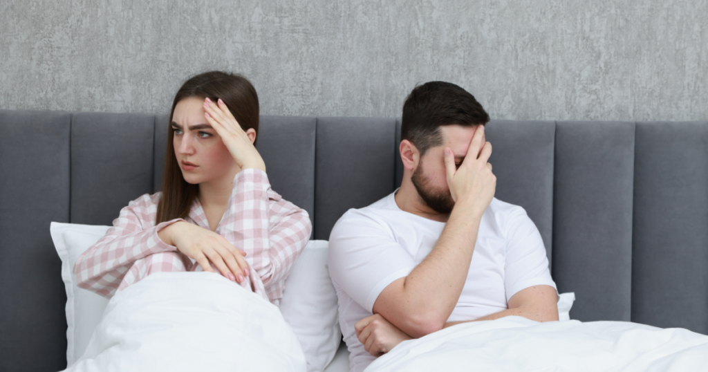 Scham im Schlafzimmer: Paar sitzt angespannt im Bett · Rückzug, Unsicherheit und Druck nach einem intimen Moment