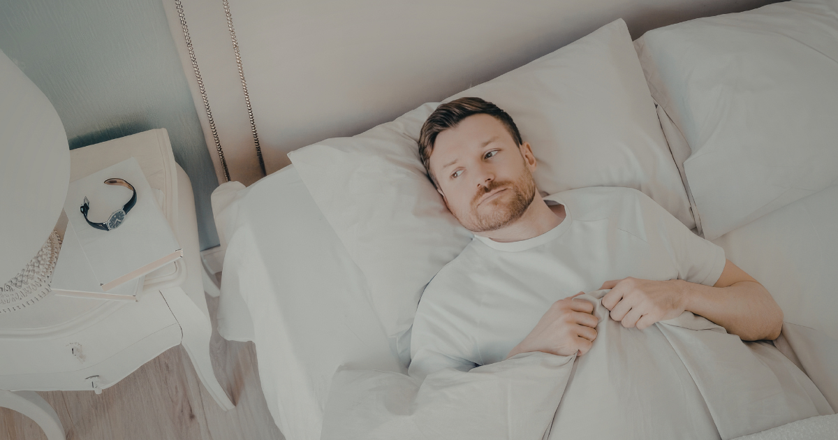 Junger Mann liegt nachdenklich im Bett – Erektionsprobleme und Leistungsangst trotz Sildenafil.