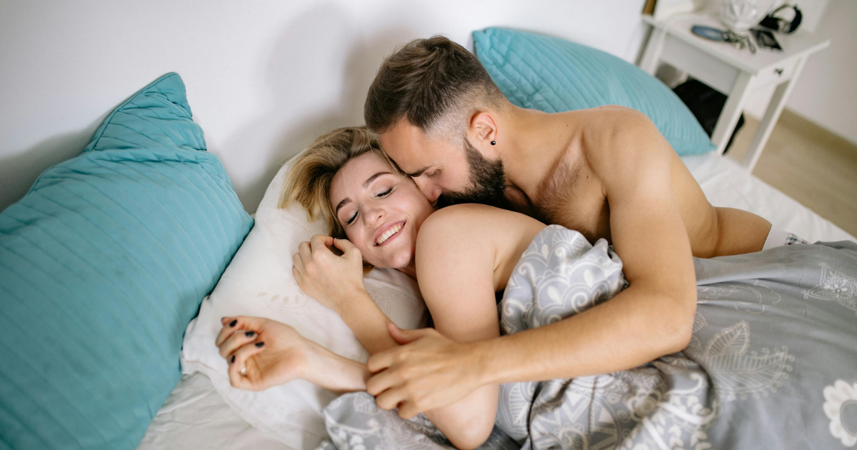 Liebespaar liegt eng umschlungen im Bett · erfüllende Sexualität in der Beziehung